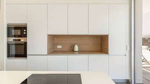 Una cuina moderna amb electrodomèstics integrats, una estant de fusta i vistes a l'exterior.