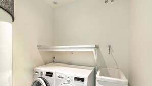 A laundry room with two front-loading washing machines and a stacked washer-dryer unit.
