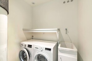 A laundry room with two front-loading washing machines and a stacked washer-dryer unit. - Exclusive  private villa with endless ocean views (Adeje)