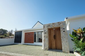 Una casa moderna con ingresso in pietra, un'ampia finestra e vialetto lastricato.