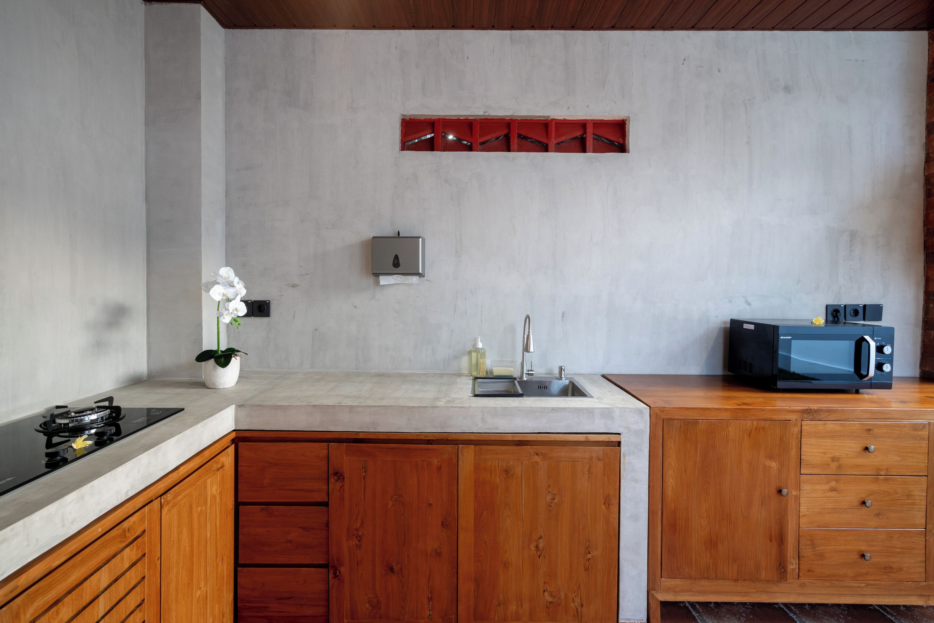 Une cuisine moderne dotée d’un îlot central, de meubles en bois, d’un four à micro-ondes encastré et d’un petit évier.