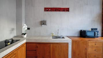 Une cuisine moderne dotée d’un îlot central, de meubles en bois, d’un four à micro-ondes encastré et d’un petit évier.