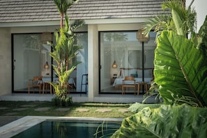 Una casa moderna con piscina, amplias ventanas y mobiliario exterior.