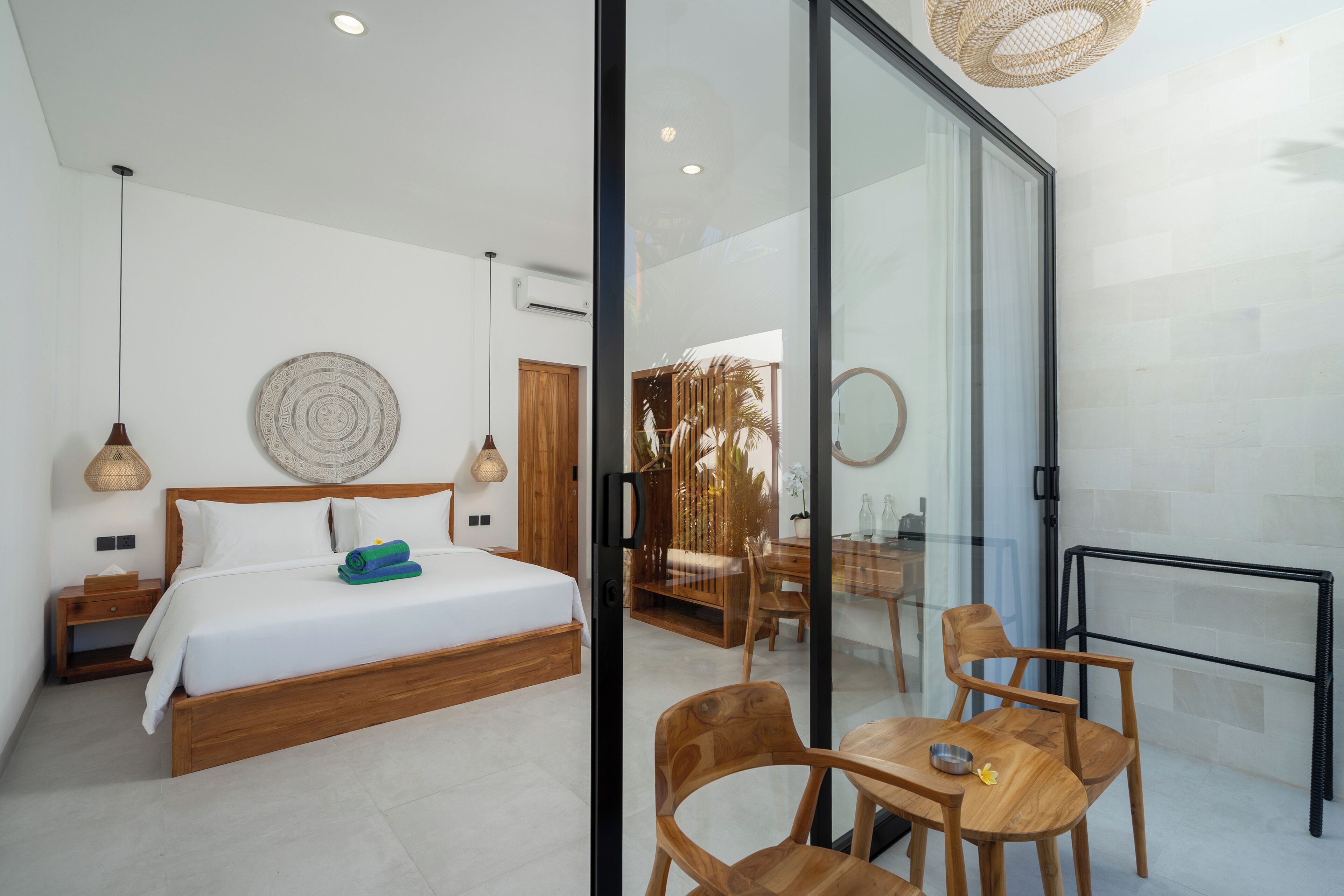 A modern bedroom with a bed, bedside tables, and a glass partition.