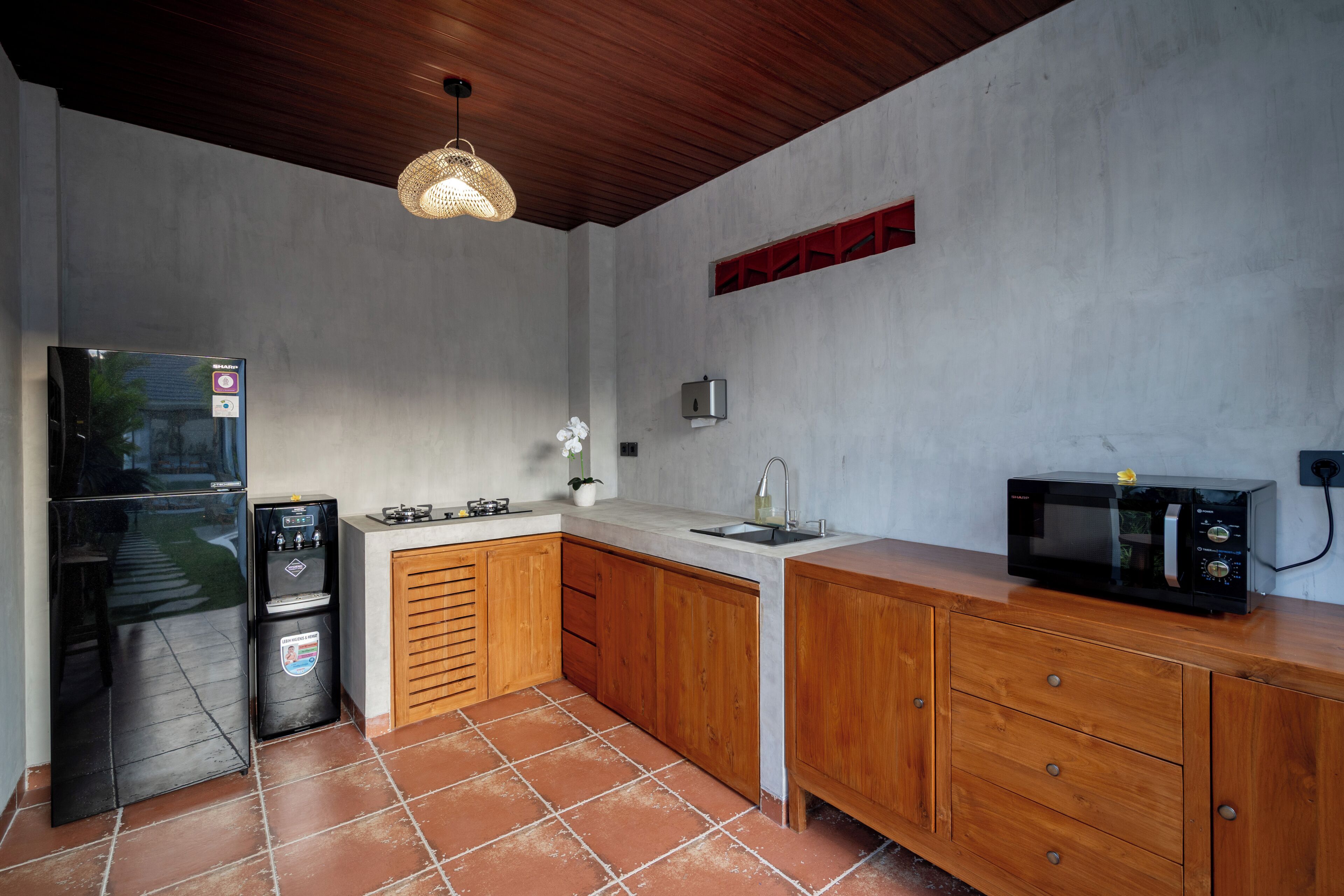 A compact kitchen with a gas stove, a microwave, a sink, and a water dispenser.