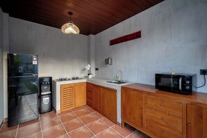 Una cucina compatta con fornello a gas, forno a microonde, lavello e erogatore d'acqua.