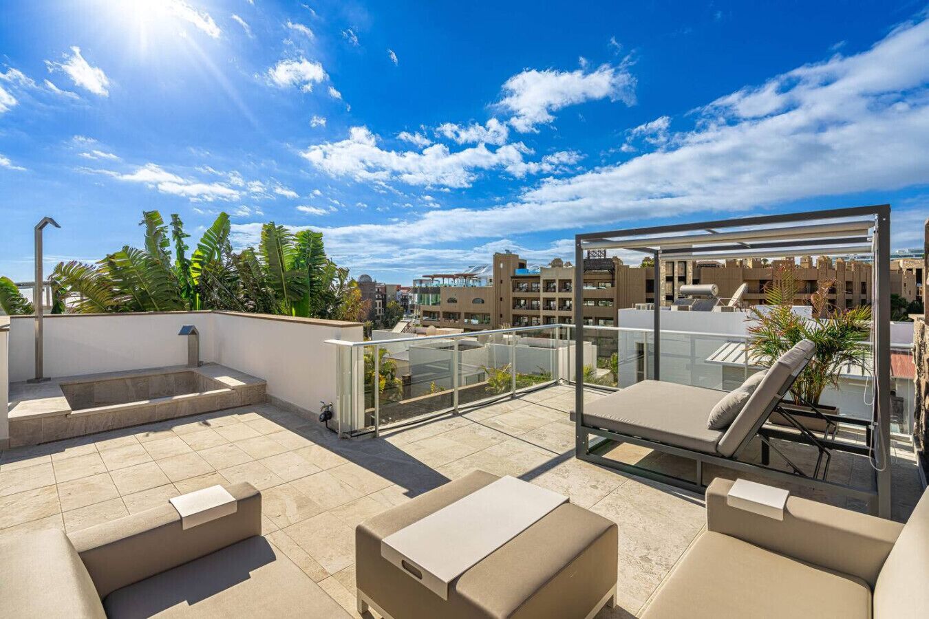 A rooftop terrace with a glass balustrade, outdoor seating, and a view of the cityscape.