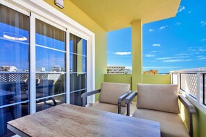 Ein Balkon mit Tisch und Stühlen, Blick auf Gebäude und einen klaren Himmel.