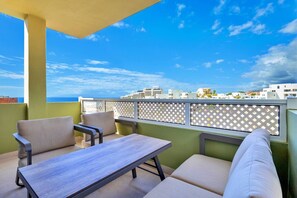 A balcony with a table and chairs, a view of buildings, and a clear sky. - 1bedroom ocean view apartment (Costa Adeje)
