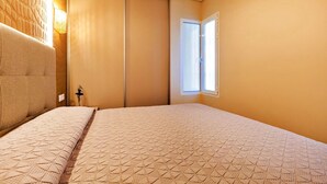 A bedroom with a bed, a wall-mounted light, a window, and a door. - 1bedroom ocean view apartment (Costa Adeje)