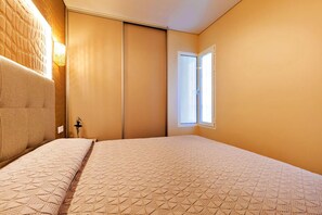 Ein Schlafzimmer mit einem Bett, einer Wandleuchte, einem Fenster und einer Tür.