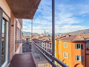 A balcony with a view of a cityscape, including buildings and a distant tower.