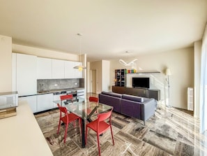 A modern living space with a dining area, kitchen, and seating area.