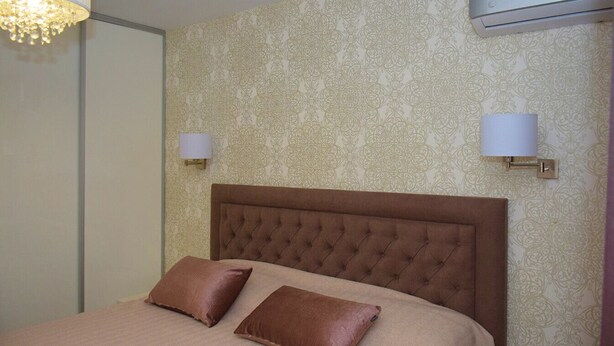 Habitación de hotel con cabecero capitonado, dos lámparas de pared y un equipo de aire acondicionado.