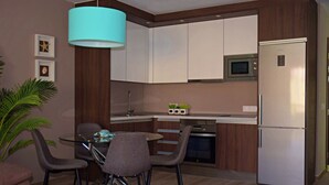 Una cocina moderna con gabinetes blancos, un refrigerador de acero inoxidable y un comedor con mesa y sillas de vidrio.