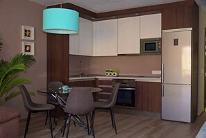 Eine moderne Küche mit weißen Schränken, einem Edelstahlkühlschrank und einem Essbereich mit Glastisch und Stühlen.