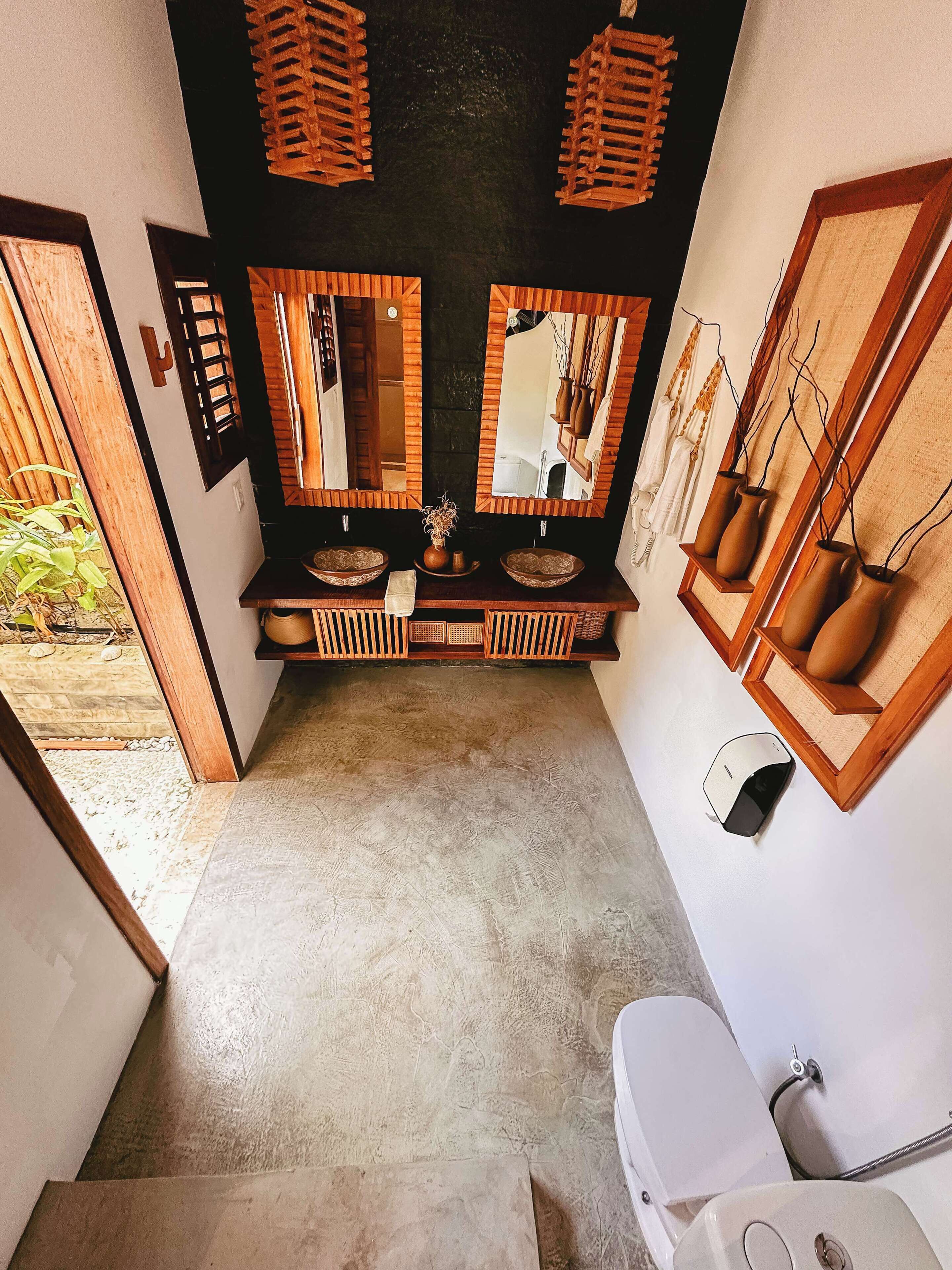 A bathroom with a double sink, two mirrors, and a toilet.