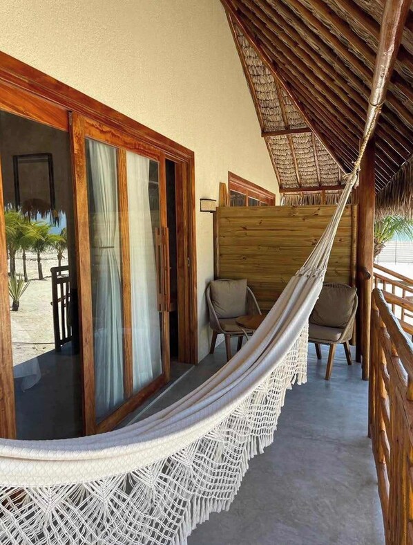 A hammock on a balcony with wooden railings and a view of the beach. - Chalet deluxe beira mar (Cruz)