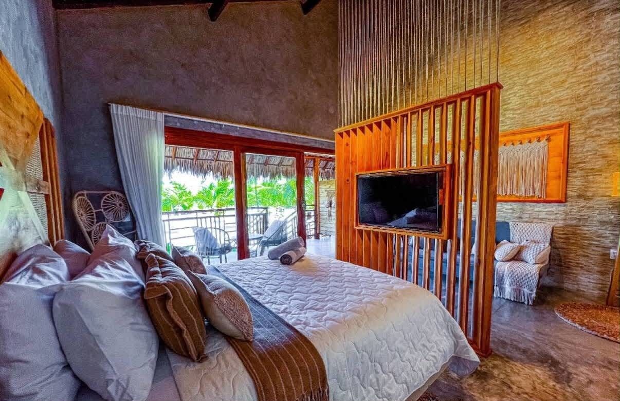 Un dormitorio con una cama grande, televisión y vistas a zonas verdes.