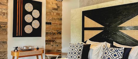 A well-appointed bedroom with a large bed, a wooden headboard, and a stone wall.