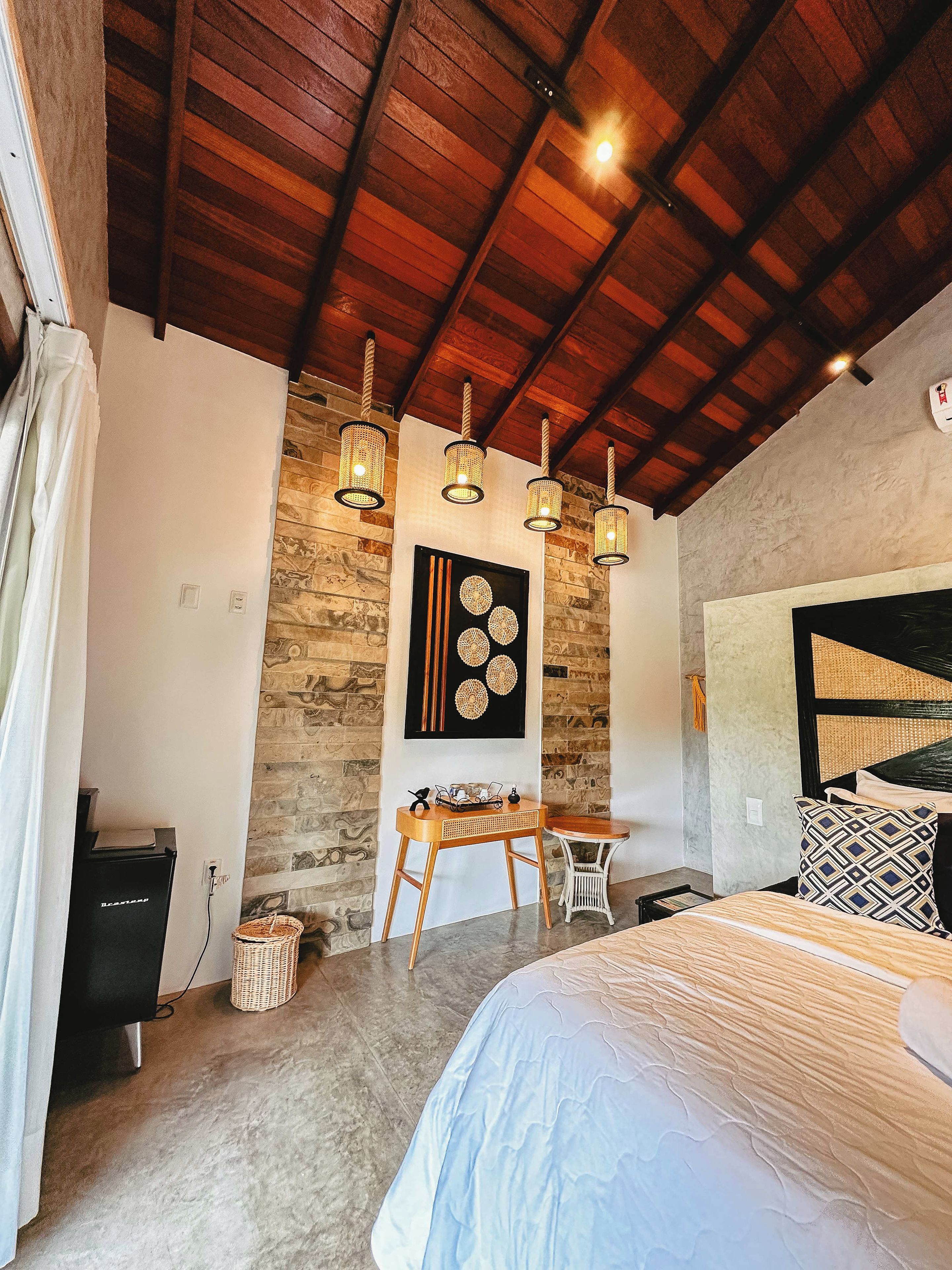 Une chambre à coucher comprenant un lit, un bureau, une chaise, une lampe et une œuvre d’art accrochée au mur.