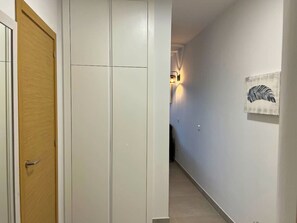 Ein Flur mit einer Holztür, einem weißen Kleiderschrank und einer Wandleuchte.