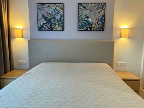 Ein Hotelzimmer mit einem großen Bett, zwei Nachttischlampen und zwei an der Wand hängenden Bildern.