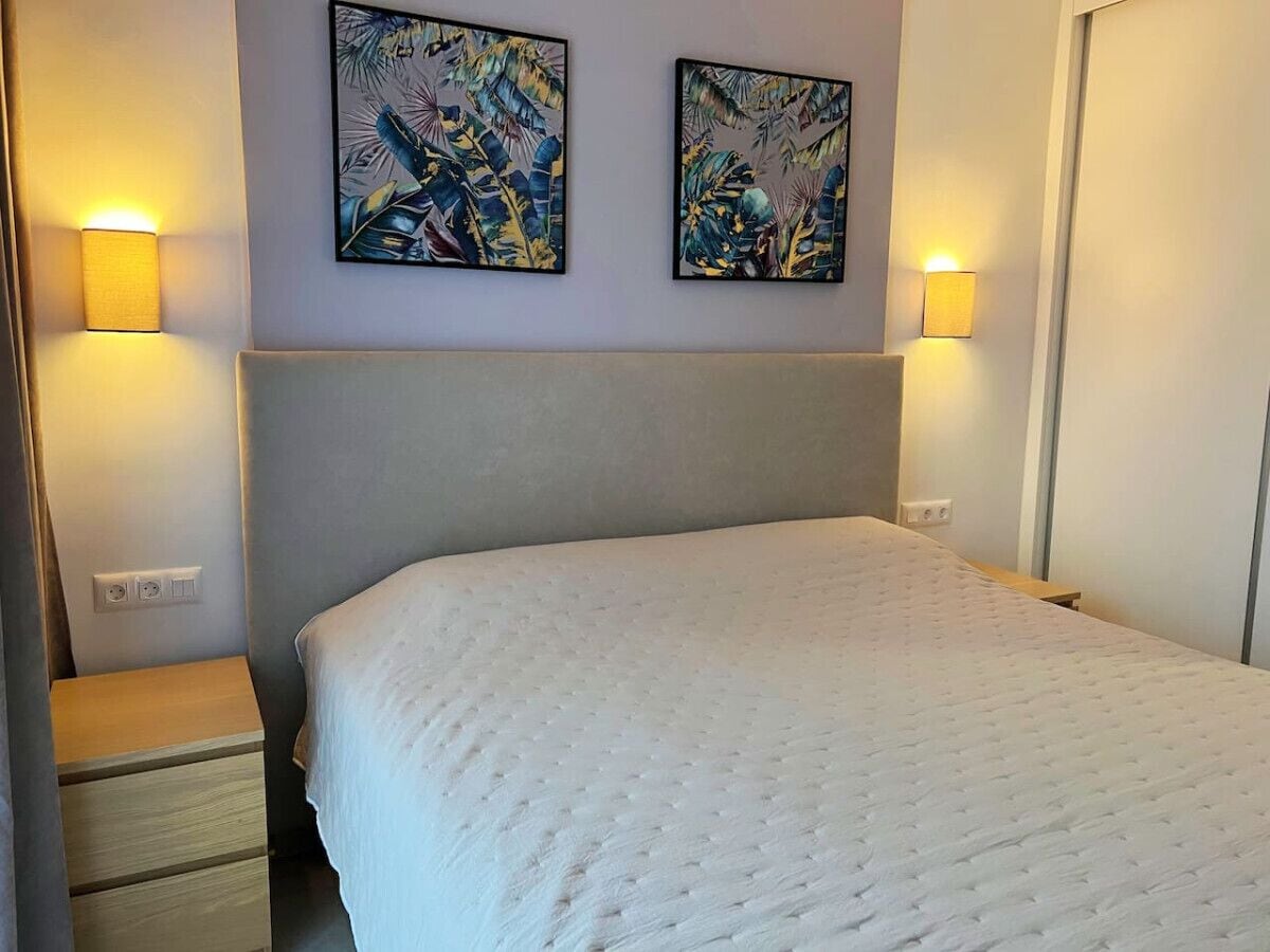Ein Hotelzimmer mit einem Bett, zwei Wandleuchten und zwei Kunstwerken an der Wand.