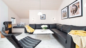 Ein modernes Wohnzimmer mit einem Ecksofa, einem kleinen Tisch, einem Kamin und zwei gerahmten Bildern an der Wand.