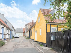 Un carrer estret flanquejat per cases europees tradicionals, un cotxe estacionat i una closca de correu a la dreta.