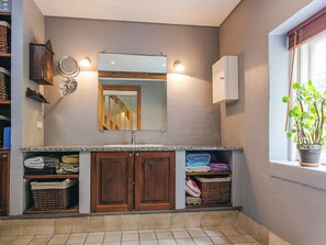 Un bany amb un doble lavabo, armaris de fusta, un mirall i una planta en test amb vistes a la finestra.