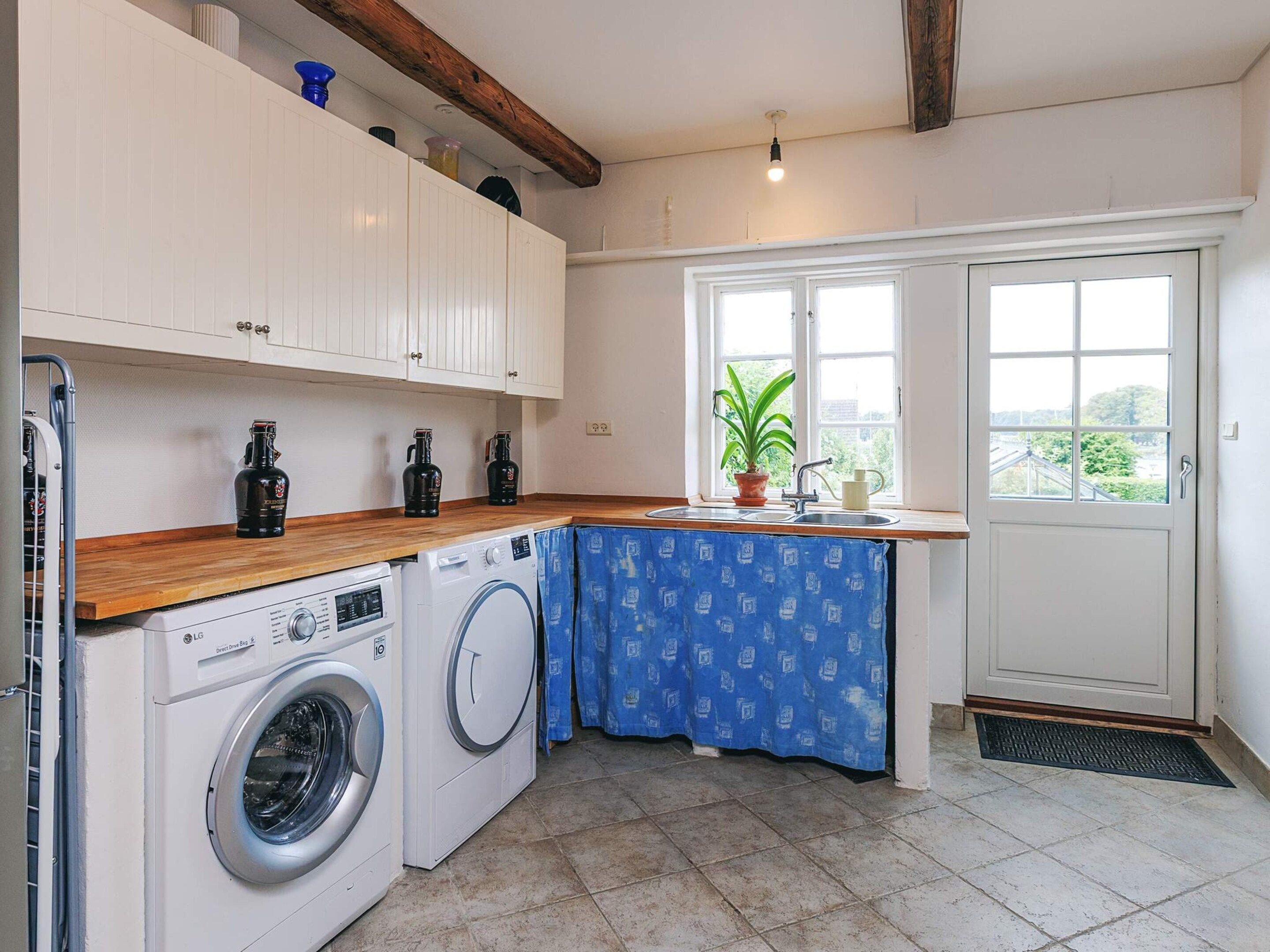 A laundry area with a washing machine, dryer, and a sink with a potted plant.