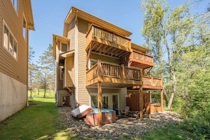 A multi-story wooden house with a balcony, a hot tub, and outdoor seating. - New! Lake Area Townhome w/ Hot Tub (McHenry)