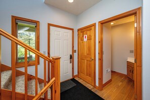 A hallway with wooden doors, a staircase, and a view of the outdoors. - New! Lake Area Townhome w/ Hot Tub (McHenry)