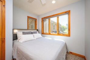Une chambre à coucher avec un lit, une table de chevet, une fenêtre et une porte.