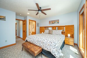 Ein Schlafzimmer mit einem Bett, einer Bank, einem Nachttisch, einem Deckenventilator und einem Gemälde an der Wand.