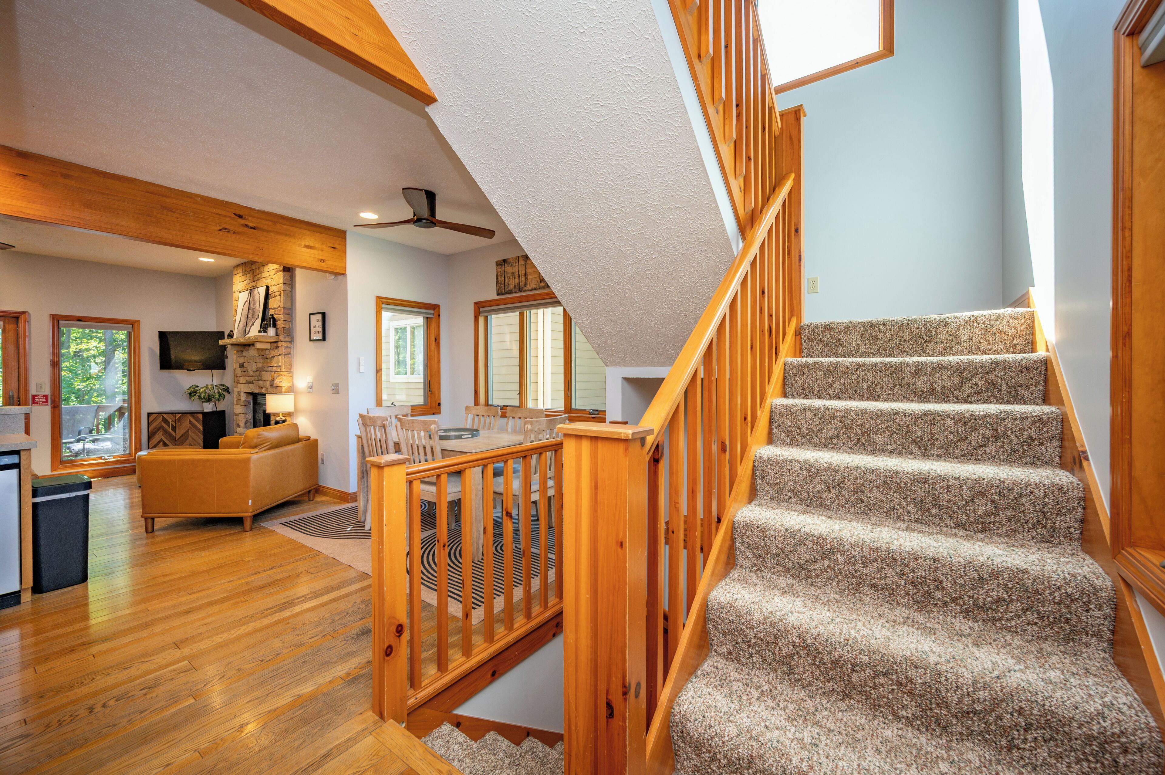 A spacious living area with a wooden staircase, a kitchen, and a dining area.
