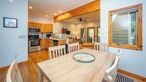 Una cocina moderna con armarios de madera, electrodomésticos de acero inoxidable y un comedor con mesa y sillas de madera.