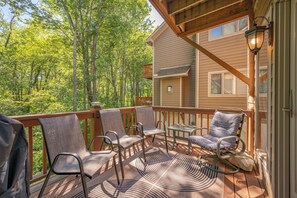 Une terrasse en bois avec des meubles d’extérieur, une pergola et une vue sur une forêt.