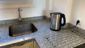 A kitchen with a stainless steel sink, a kettle, and a countertop with a metal rack. - Ocean-View Apartment with Pool in Los Gigantes (Santiago del Teide)