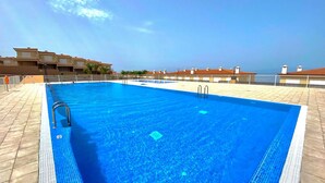 A rectangular swimming pool with two ladders on one side, surrounded by a tiled deck. - Ocean-View Apartment with Pool in Los Gigantes (Santiago del Teide)