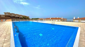 Ein rechteckiger Pool mit zwei Leitern an einer Seite, umgeben von einer gefliesten Poolterrasse.