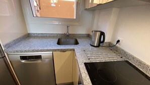 A kitchen with a dishwasher, a kettle, and a stovetop. - Ocean-View Apartment with Pool in Los Gigantes (Santiago del Teide)