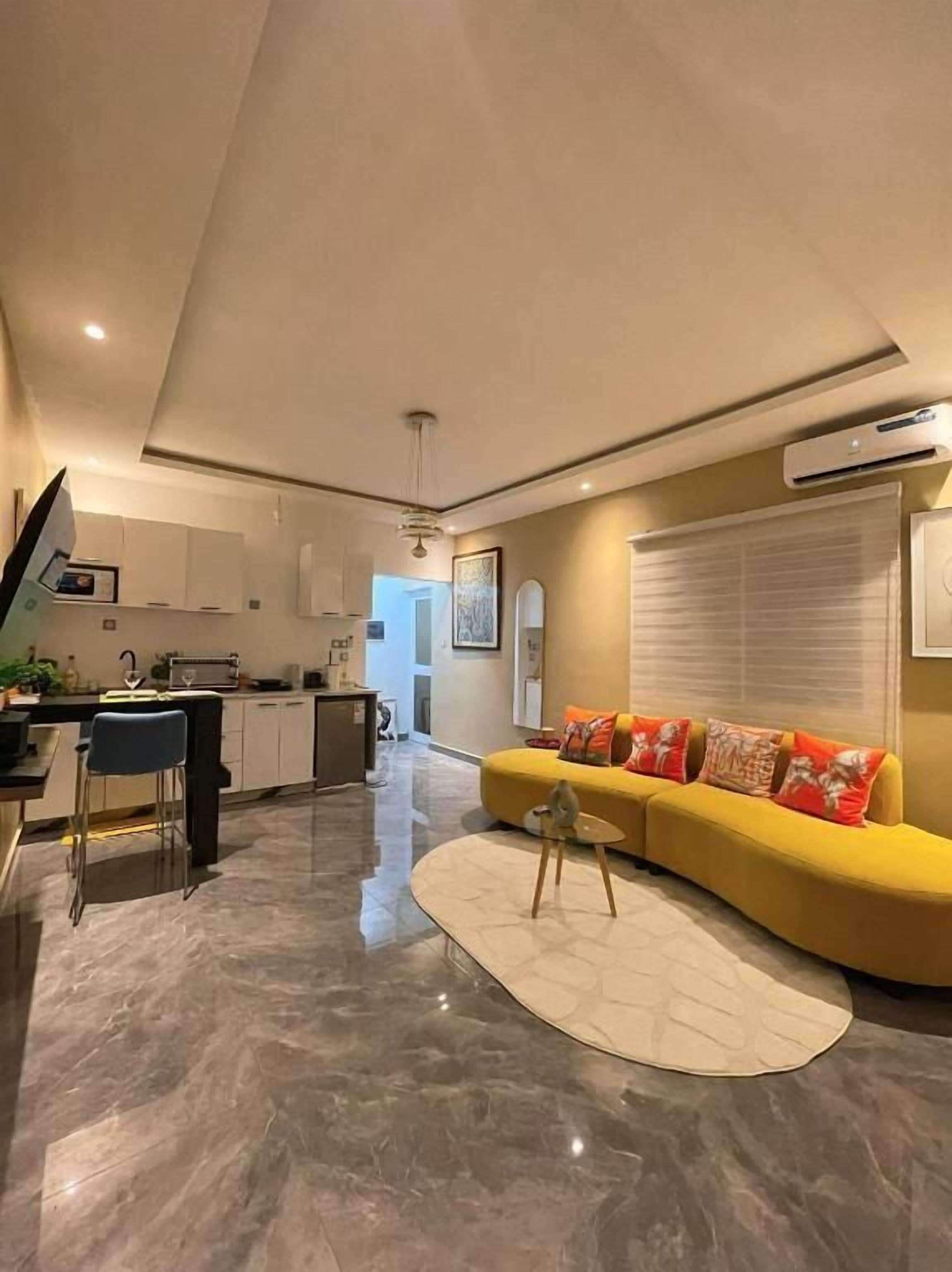Un espacio habitable moderno con cocina, comedor y un sofá amarillo con cojines.