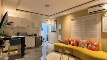 Un espacio habitable moderno con cocina, comedor y un sofá amarillo con cojines.