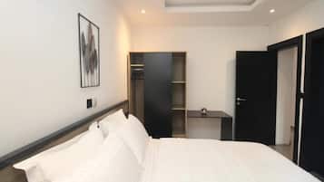 Ett hotellrum med en säng, en garderob, ett litet bord och en klädkammare.