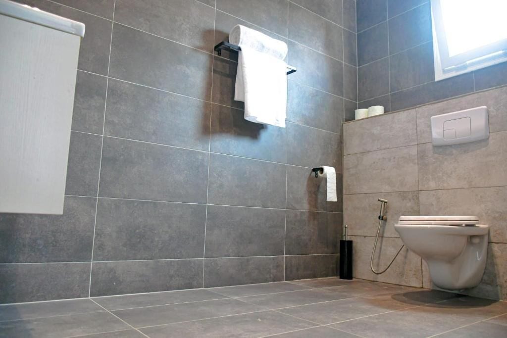 Un baño moderno con inodoro, toallero y secador de manos.