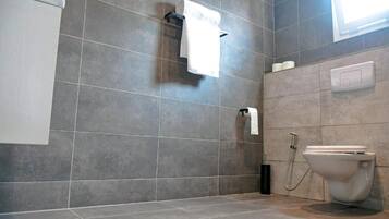 Un baño moderno con inodoro, toallero y secador de manos.