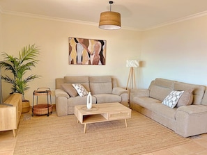 Ein Wohnzimmer mit zwei Sofas, einem Couchtisch, einer Stehlampe und einem Gemälde an der Wand.