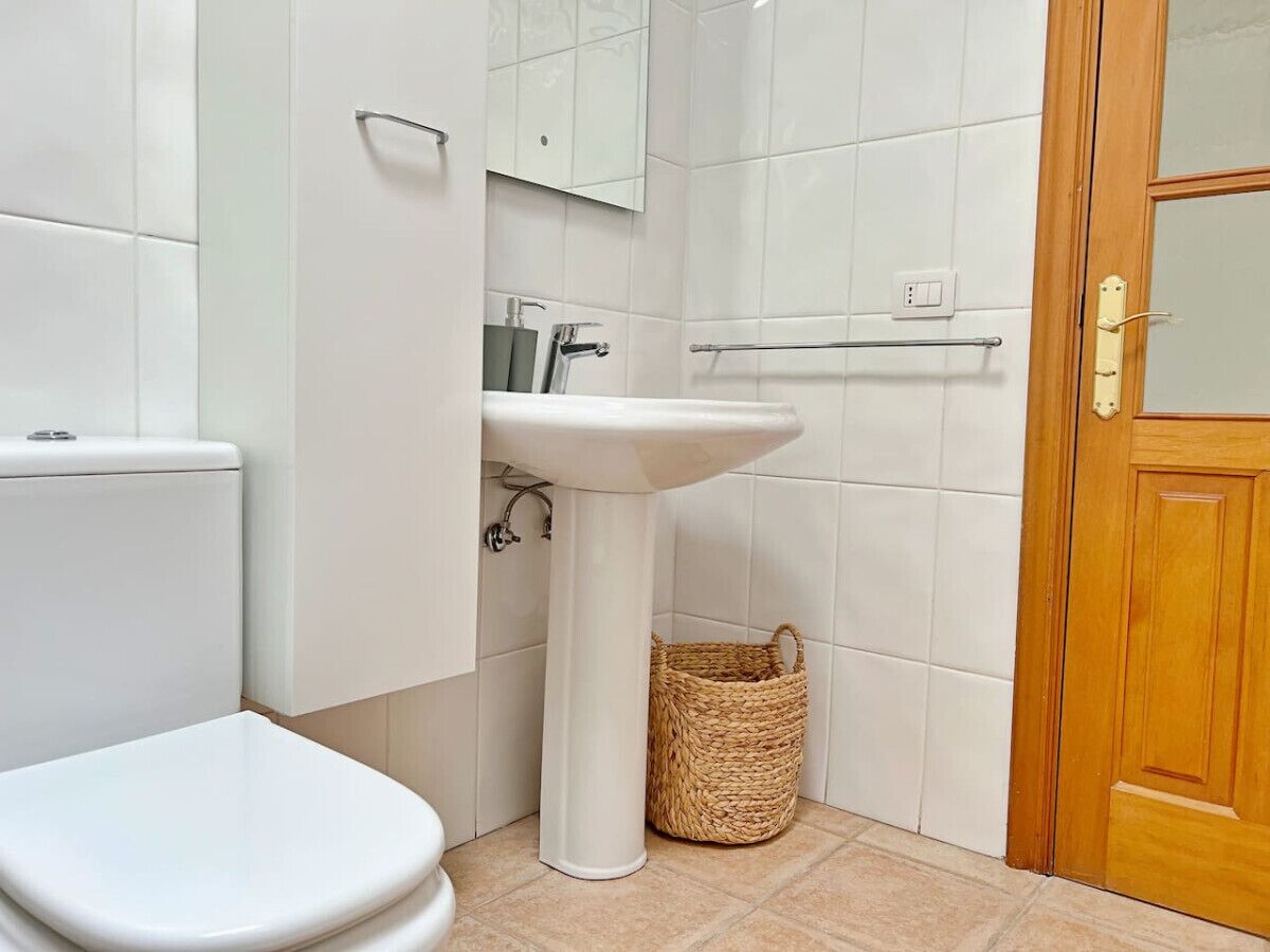 Een badkamer met toilet, wastafel en een houten deur.